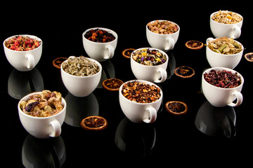 Various kinds of herbal tea ingredients in cups over black background. Natural herbs medicine.