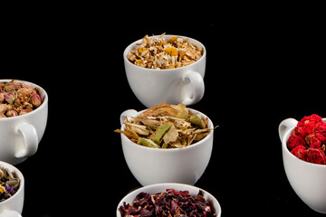 Various kinds of herbal tea ingredients in cups over white background. Natural herbs medicine.