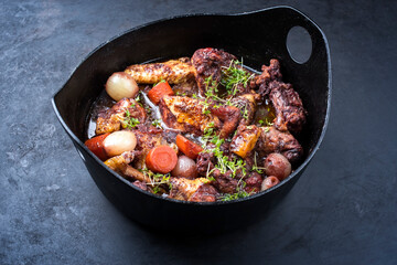 Modern style traditional French coq au vin with vegetable marinated in Burgundy sauce as close-up in a design casserole