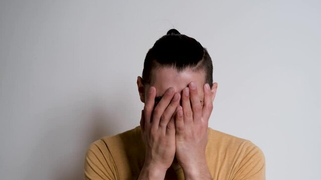 Young handsome European Caucasian man with beard shouts no and grabs his head with both hands. Person depicts the emotions of anger on white background.