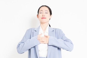 白バックの前に立って、胸に手を当てる女性