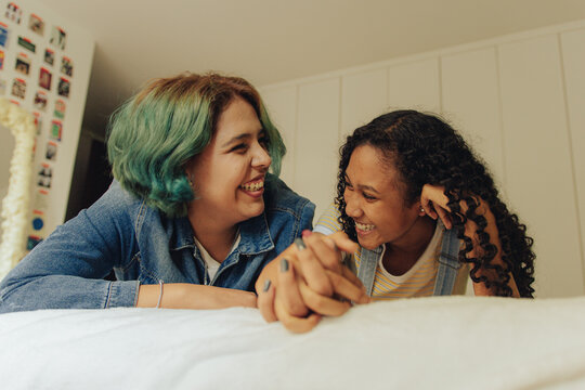 Pareja de j&oacute;venes lesbianas tomadas de la mano sobre su cama 