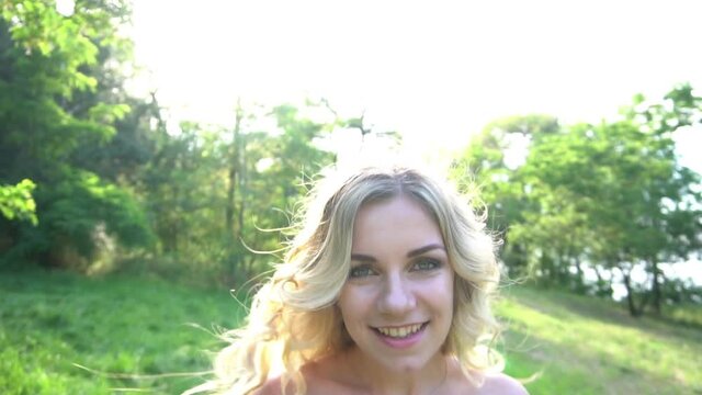 Pretty woman walk in city park, does wave by hair and smiles. Slow motion, stead