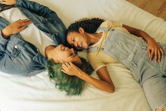 Pareja de j&oacute;venes lesbianas  descansando y sonriendo sobre su cama 