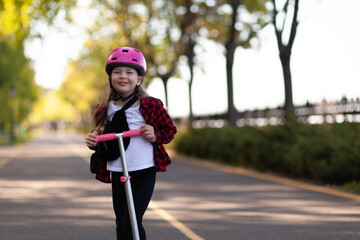 Active pastime. Portrait of a girl in a helmet on a scooter on a bicycle road in the city. An active lifestyle in childhood.