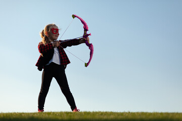 Feel free to explore the world. Little girl hunts with a bow. Superhero game. Strong and confident child, imagination.