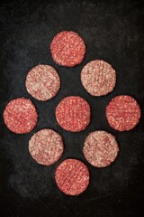 Fototapeta na wymiar Raw Minced Steak Burgers from Beef and Pork Meat on Black Background, Overhead View. Raw Ground Beef, Round Patties for Cooking Homemade Burger On BBQ Grill, Top View