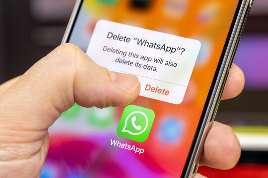 Man is about to delete the WhatsApp from a smartphone, close-up. Removing WhatsApp app. Protection personal data and privacy. Russia, Moscow - March 7, 2021