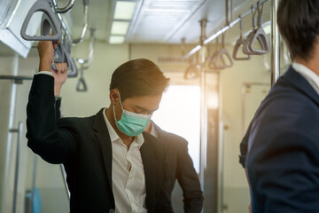 Business people with surgical mask face protection while traveling to work and keep social distancing to crowd  in the metro.