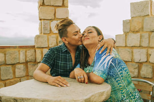 Joven gay abraza y besa a su madre mientras esperan sentados 