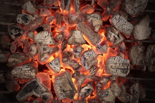 BBQ Grill Pit With Glowing And Flaming Hot Charcoal. Hot Charcoal In Barbecue Grill Pit With Flames Background Texture, Close-up. Flaming Charcoal In Grill Pit Isolated On Black Background.