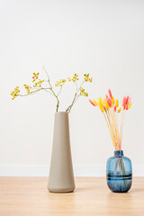 Frontal image of green blueberry branches in an elongated gray vase