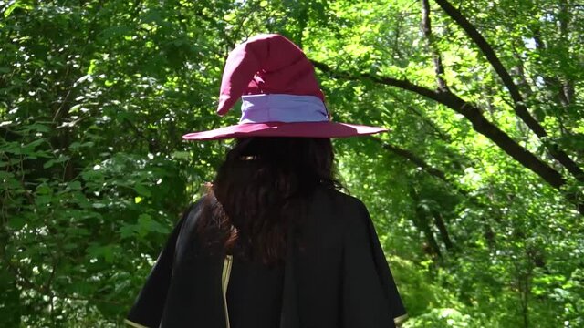 Woman witch in a hat and clothes in the forest gesticulate with her hands