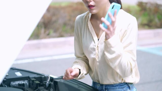 自動車のボンネットを開ける女性　故障　ロードサービス