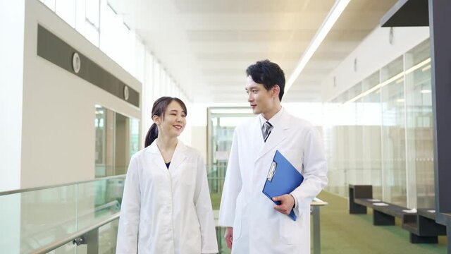 室内を歩く白衣の男女　医師　科学者
