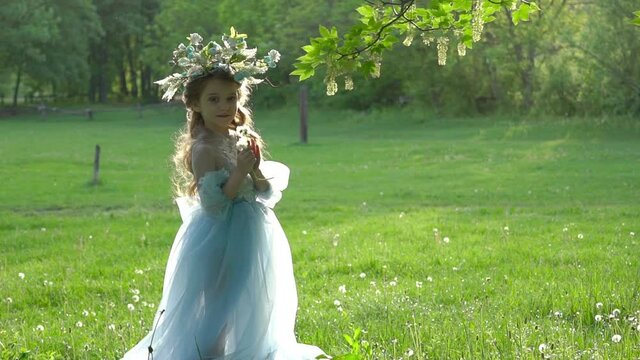 A little girl in nature in a light dress send a kiss