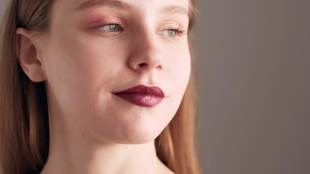 Beautiful woman. Contrast makeup. Fashion model. Perfect skin. Tender smiling lady with pastel eyeshadow bright accent lipstick isolated beige.