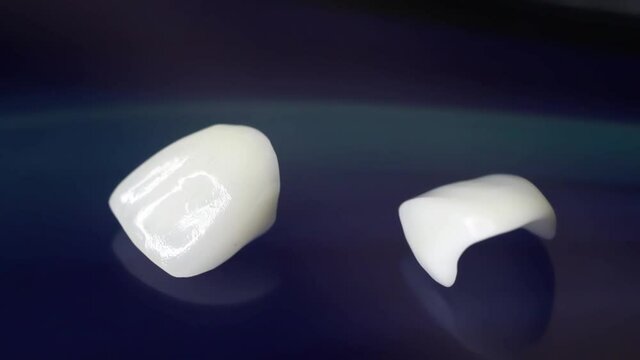 Ceramic dentures and crowns on black background. Top view on set of single dentures and dental crowns. Zirconium crown and zirconium hybrid press on isolated black background. 