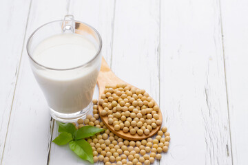 Soy and soy milk in a glass with soybeans in wooden bowl background