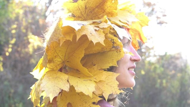 Slow Motion Portrait of charming young woman wearing a wreath of autumn leaves. 