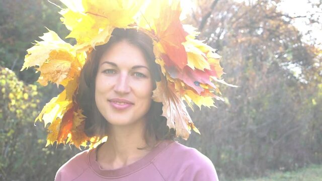 Slow Motion Woman with autumn wreath looking on camera outdoors