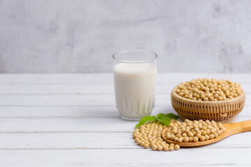 Soy and soy milk in a glass with soybeans in wooden bowl background