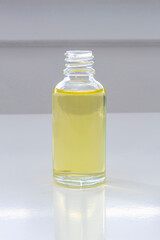 An open cannabis oil transparent bottle on a white table.