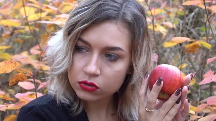 Slow Motion Beautiful blonde charismatic girl holding red apple in the park - Powered by Adobe
