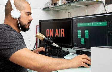 Hombre latino haciendo una transmisión en lineá de un podcast, usando un micrófono y su ordenador