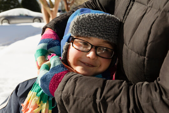 Mother hugging son wearing winter hat and glasses