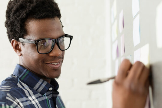 Young man wearing glasses writing on adhesive note
