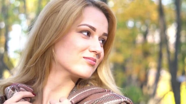 Young attractive blond woman outdoors on fall background. Autumn portrait of bea