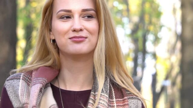 Slow Motion Blonde woman relaxing in autumnal park at sunny day