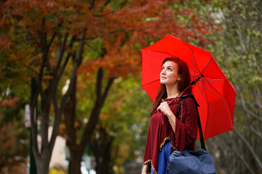 Young woman with red hair, holding red umbrella