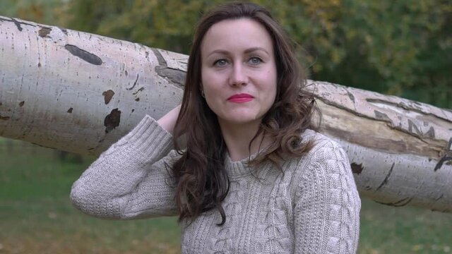 Slow Motion Beautiful brunette sitting on a tree in a an autumn park