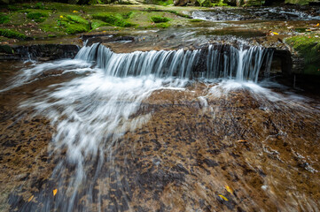 Obraz premium Upper base of the Pinaisara waterfall, with a beautiful small falls and beautiful water formation flowing through the rocks in long exposure. Iriomote Island.
