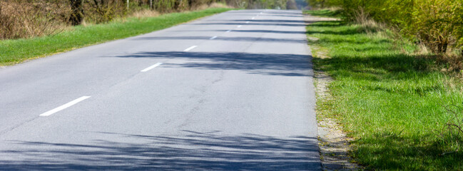 Asphalt road for transport. Shadow of trees on the road growing on the roadside.