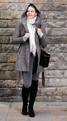 Fototapeta na wymiar girl in hood and coat standing near stone wall in autumn season