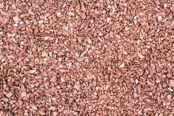 Background of small red fine gravel. Walking path cover texture with a little dry twigs