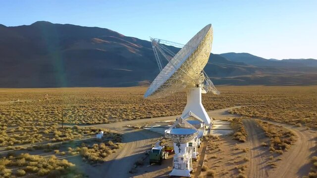 Aerial drone view around a large Satellite dish and multiple small desert arrays