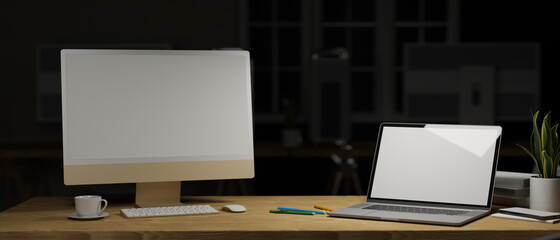 3D rendering, computer and laptop with mock-up screen on wooden table with supplies in home office at night