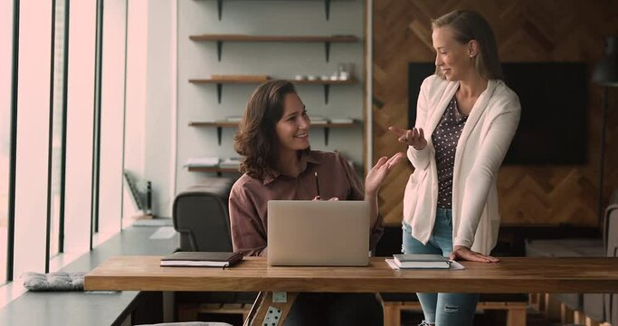 New employee company staff member look at laptop asks about corporate app program software receiving helpful information from trainer young blond friendly colleague. Mentoring, apprenticeship concept