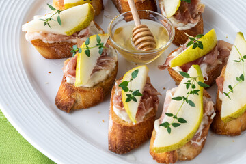 Close up view of a platter of pear and prosciutto bites served with honey.