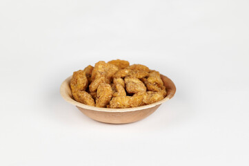 Jaggery coated banana chips or sharkara varatti in an areca leaf bowl on a white background