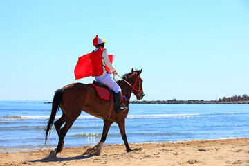 Race horse and jockey galloping on the beach