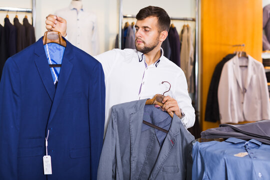 guy is considering an assortment of stylish jackets in a men's clothing store