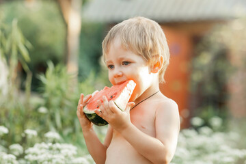 Portrait of cute handsome in nature. Funny kid eating watermelon outdoors in summer park. Happy...