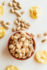Pile of pistachios in the bowl and some dry pineapples. Healthy vegetarian protein nutritious food. Vegetarian food concept.