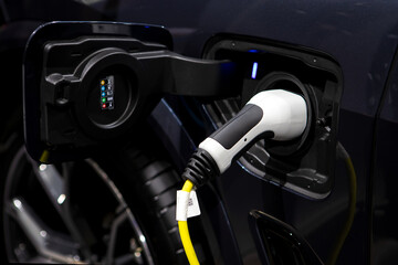 Fototapeta na wymiar Charging cable plugged into the side of electric car, Car or Electric vehicle, Eco-friendly sustainable energy concept.