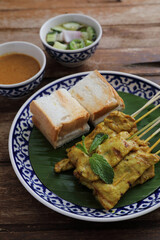 Local Thai food pork satay with oeanut dipping sauce isolated in wood background